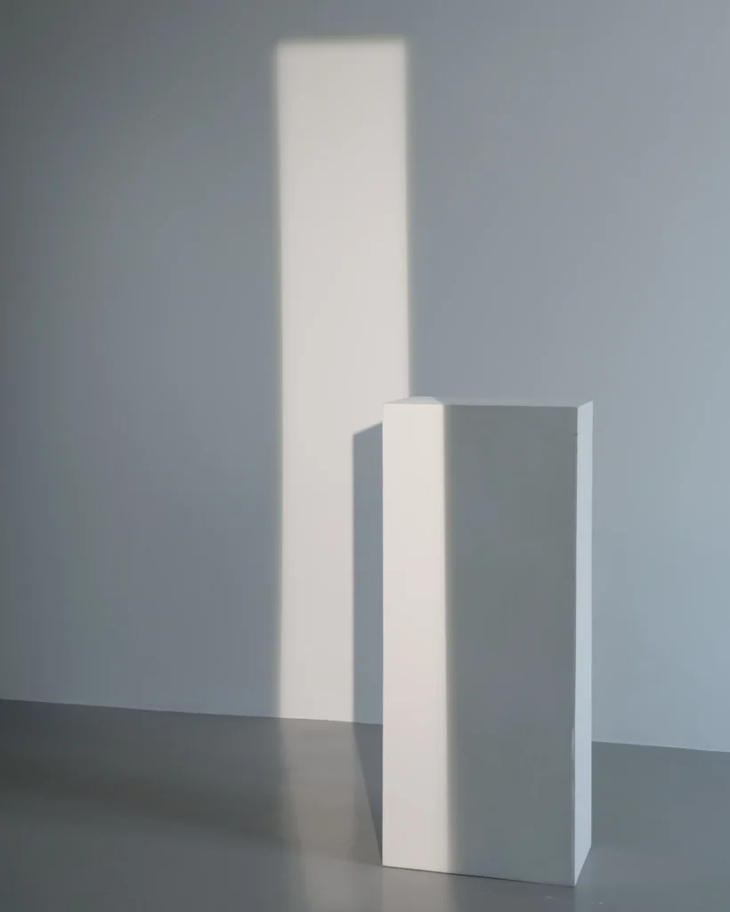 Colonne isolée dans une pièce blanche baignée de lumière.